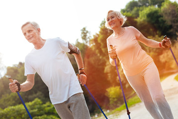 Delighted elderly couple practicing Nordic walking