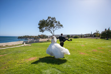 Couple smiling and embracing near wedding arch on beach. Honeymoon on sea or ocean