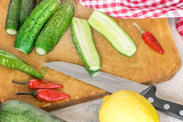 Fresh green sliced cucumbers, chilli, lemon on kitchen wooden cutting board. Cooking vegetable salad