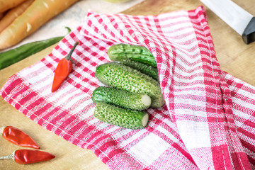 Fresh green cucumbers and red small chilli on kitchen Tissue napkin. Preparation for salting