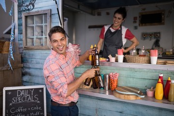Portrait of happy man holding beer bottles at counter