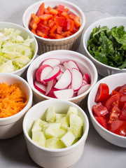 Mix of vegetable bowls for salad or snacks on gray background. Diet detox concept