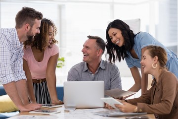 Team of executives discussing over laptop in the office