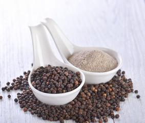 Black peppercorns powder on white wooden