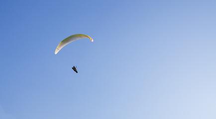 Man flying with paraglider, copy space, clear blue sky 