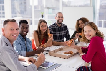 Portrait of executives having pizza in conference room