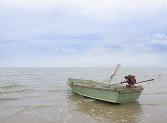 Naklejka na ściany i meble Green small fishing boat in the sea and sky background.