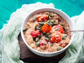 Quinoa porridge with strawberries and pumpkin seeds in bowl. Light dairy and gluten free breakfast