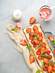Home made strawberry not baked cheese cake in oven tin on gray background with flowers