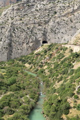 The train tracks crossing the rock by a tunnel, next to the river Guadalhorce in Caminito del Rey, Malaga, Spain