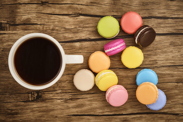 Colorful macaron and cup of coffee with wooden table