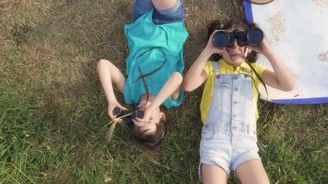 Young Girls Looking at Sky with binoculars in green field in Italy