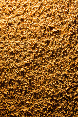 Plaster on a wall in gold lighting as a background