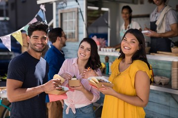 Portrait of friends standing with snacks