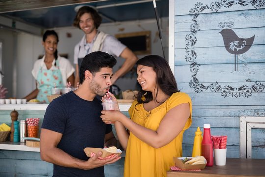Woman feeding juice to man