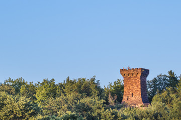 stone tower and tourists on forested bluffs