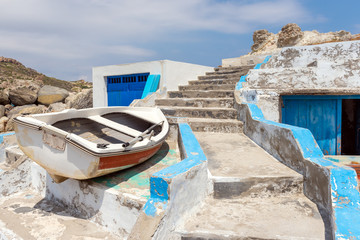 Fishing boat, stairs and traditional boat houses in Mandrakia village on the coast of Milos island, Cyclades, Greece. © vivoo