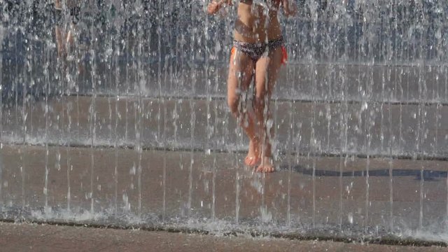 Child jumping and Playing in urban fountains, slow motion