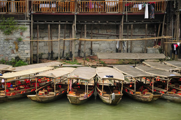 Fototapeta na wymiar Chinese tourists boats docked along a bank of the Tuo Jiang River in the village of Fenghuang China in Hunan province.