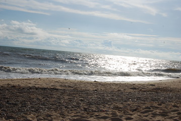 Mélange roche sable avec reflet du soleil sur les vagues