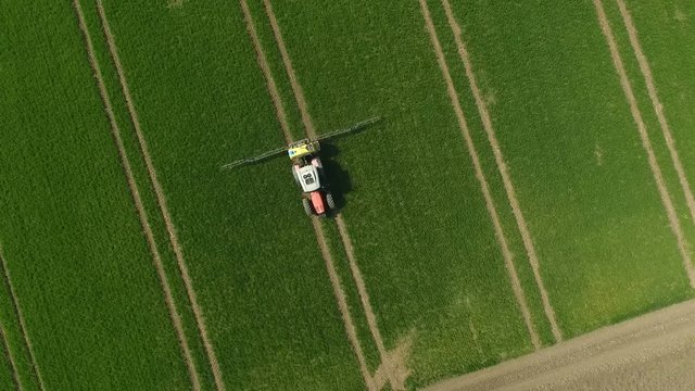The Protection Of Plants.Tractor Spraying A Green Wheat Field. Aerial View