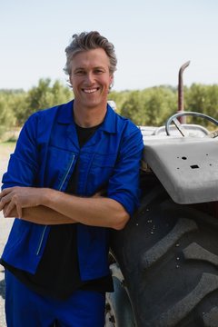 Worker leaning with arms crossed near tractor