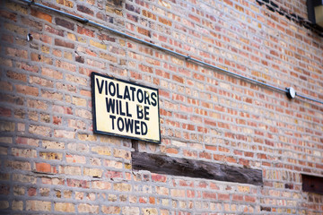 Violators will be towed sign on a brick wall