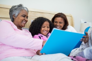 Fototapeta premium Family watching photo album together in living room