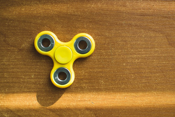 Rotating yellow fidget device lures on the background of the table alder top View. Playing with a...