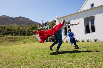 Mother and son in superhero costume playing in the backyard