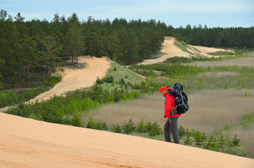 The tourist is hiking up the high dune. - 162770199