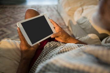Senior man using digital tablet in the living room