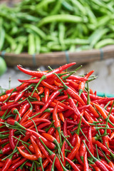 Fresh red chili peppers close up with green peppers in the background blured. Cooking ingredients. Vertical.