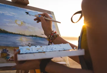Fotobehang Chocoladebruin Young woman artist painting landscape in the open air on the beach, close up  © sashafolly