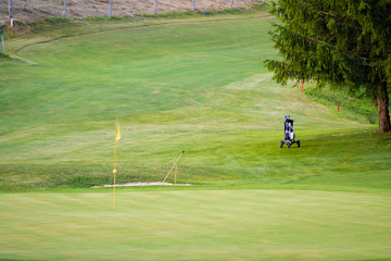 Golf course with one flag pole and trolley on fairway