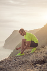 Tying running / jogging sneakers on a cliff near the sea / ocean.