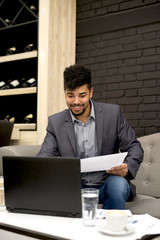 A businessman in a cafe is working on a laptop.