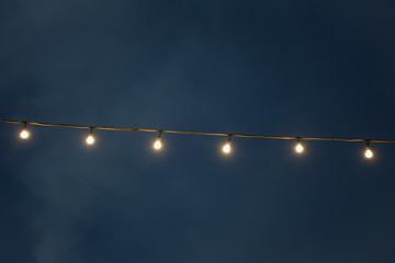 wired light bulbs lighten on the dark blue sky background