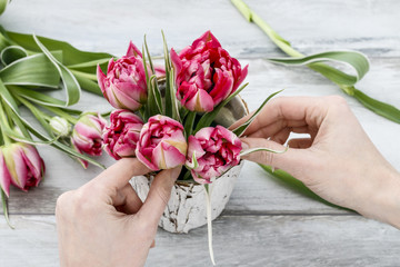 Fototapeta na wymiar Florist workplace: how to make decoration with pink tulips inside wooden box