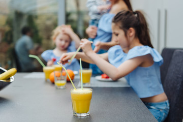 Two sisters drink juice in the kitchen