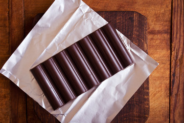 Chocolate bar on dark wooden background, top view