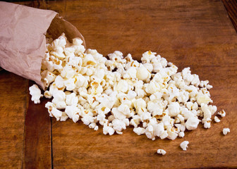 White fluffy salty popcorn in package on wooden table