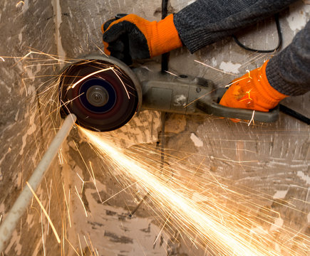 Worker cuts a metal pipe at a construction site