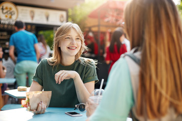 Best friends chatting on a sunny day eating tacos in park or a faire, smiling rejoicing, discussing their future healthy food startup.