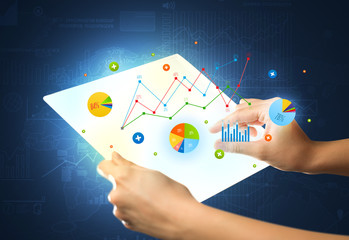 Hands touching a glass-like tablet with charts
