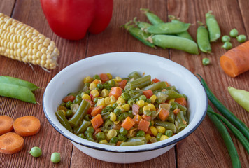 Mexican food stewed vegetables: carrots, green peas, asparagus, sweet peppers, corn. Organic vegetables on a wooden background.