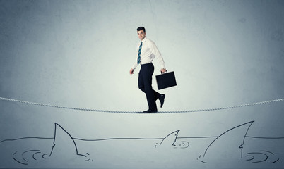 Fototapeta premium Businessman walking on rope above sharks