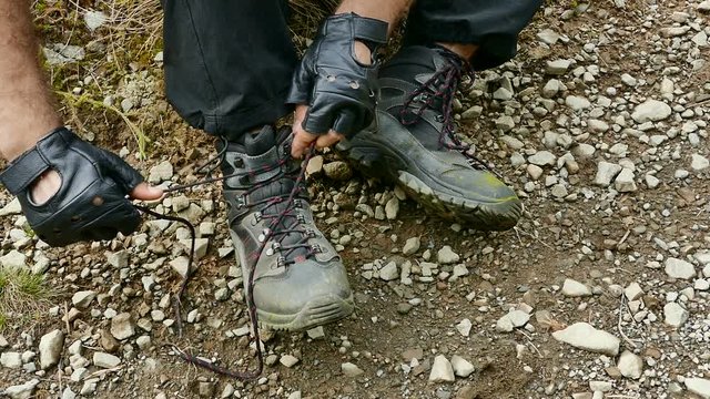 Trekking through the mountains. A man ties up his shoelaces on trekking shoes. Close-up