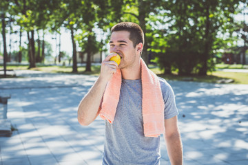 Fototapeta premium Male Runner eat apple in a Park