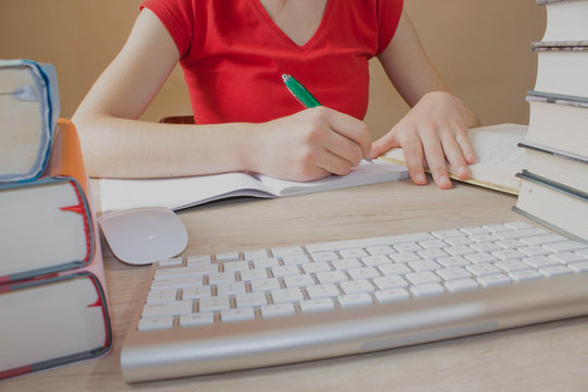 Open book, hardback colorful books on wooden table. Girl sitting at desk at home, doing homework.education concept
